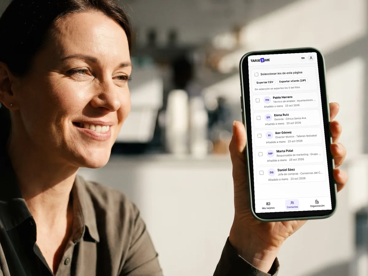 A woman smiles at the list of contacts she has received in TARJE2ME on her phone